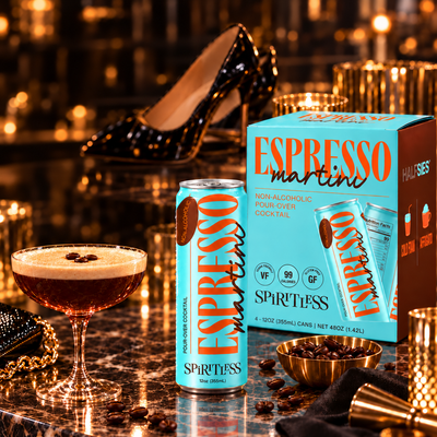 Spiritless non-alcoholic Espresso Martini can and carton on a marble bar with a coupe cocktail, gold glassware and a black high heel for a dressed-up Dry January night out